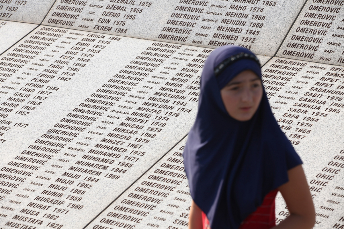 Млада Босанка минува покрај камениот споменик со имињата на жртвите од масакрот во Сребреница.