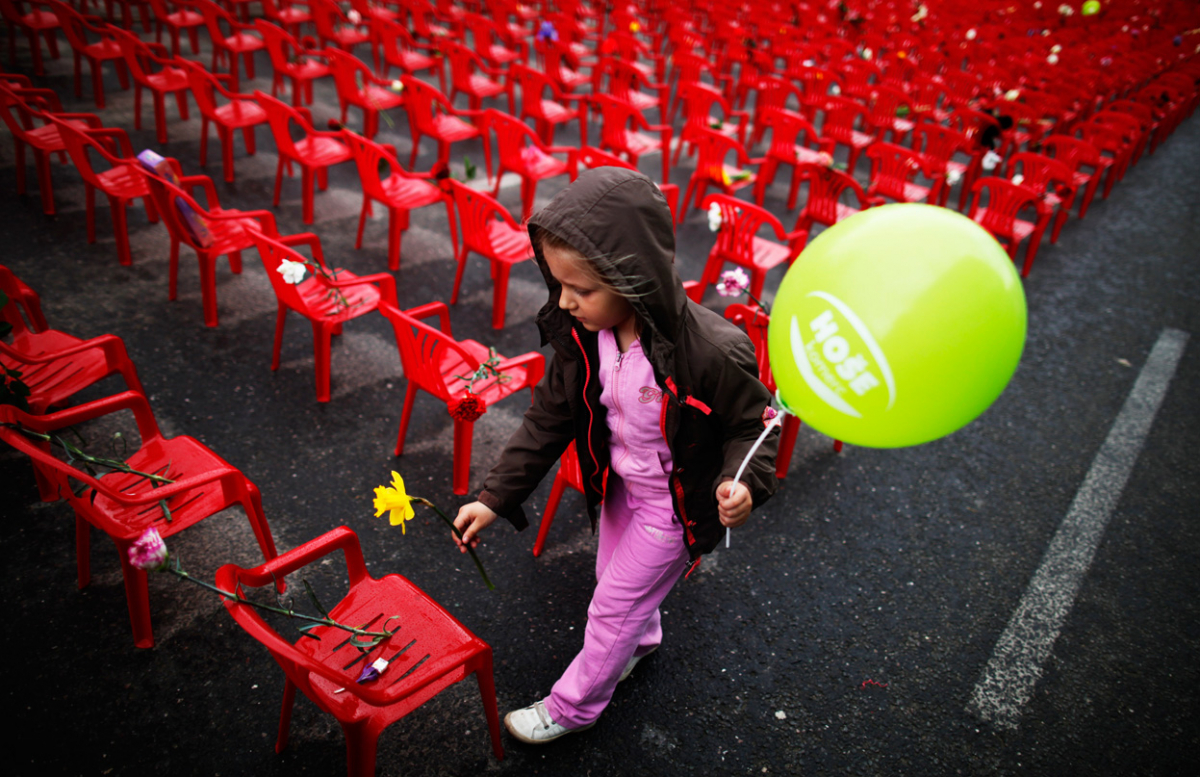 Дете остава цвеќе на неколку од "детските" столици поставени во редот на Титова улица.