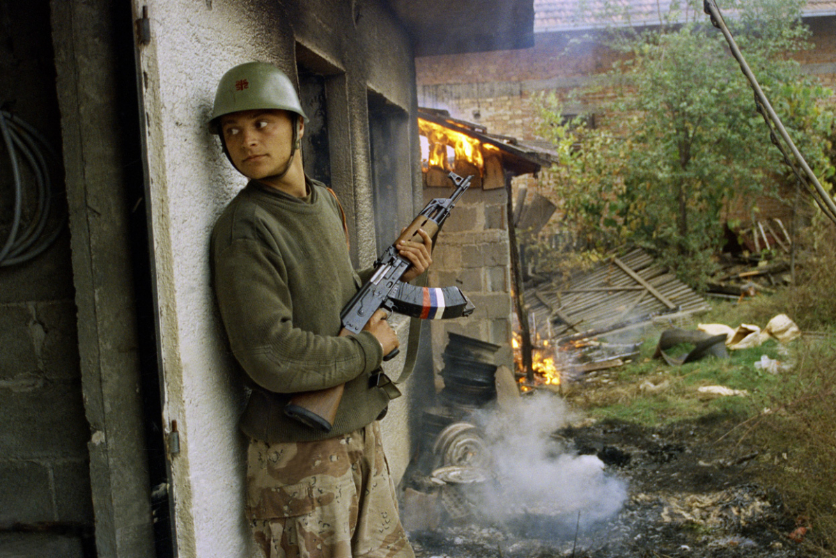 Српски војник се крие зад запалена куќа во селото Горица, 12-ти октомври 1992.