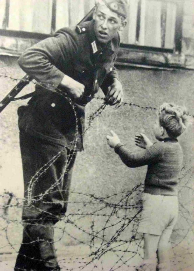 Војник му помага на дете да ја мине жицата која ќе стане Берлински ѕид